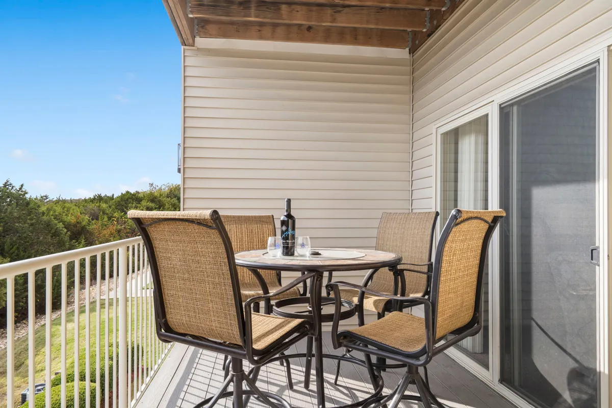 An inviting outdoor scene featuring a table set for two with a wine bottle and glasses, comfortable outdoor seating, and a sunset-lit backdrop. The seating area is positioned to enjoy the tranquil natural surroundings, creating an intimate yet open ambiance.