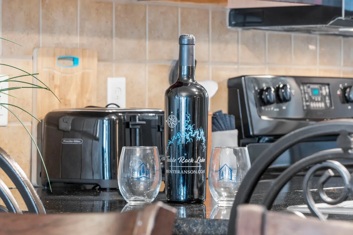 A well-appointed kitchen area with a bottle of wine and glasses set out, surrounded by modern appliances. The space suggests a relaxed, social atmosphere ideal for quiet evenings or small gatherings.
