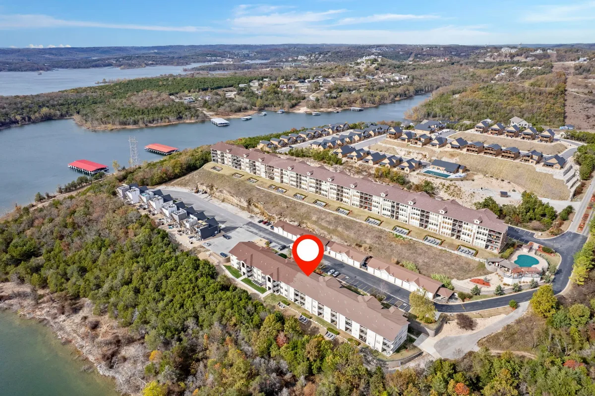 This exterior image captures a sweeping view of Table Rock Lake with surrounding hills, residential buildings, and a swimming pool. The setting suggests opportunities for water sports, outdoor fun, and group gatherings by the lake or poolside.