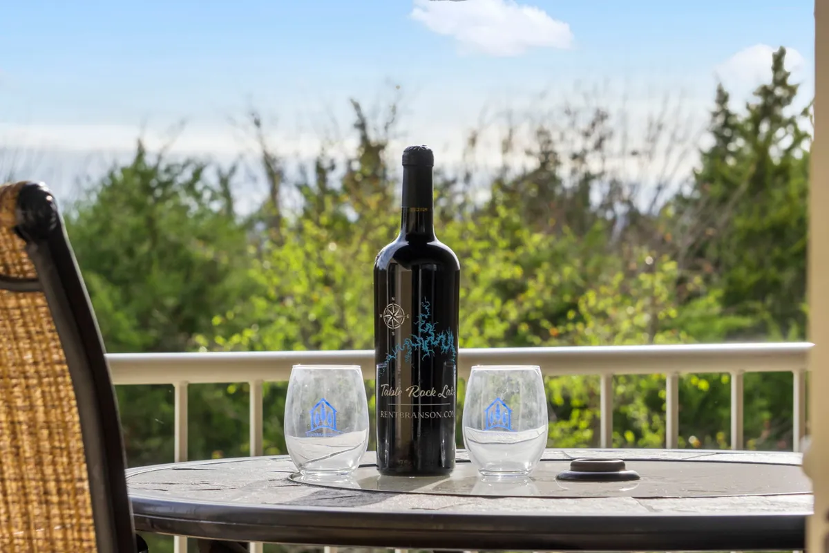 An outdoor setting with a bottle of wine and two glasses arranged on a table, framed by natural greenery. The scene evokes feelings of intimate celebration, relaxation, and savoring special moments in nature’s embrace.